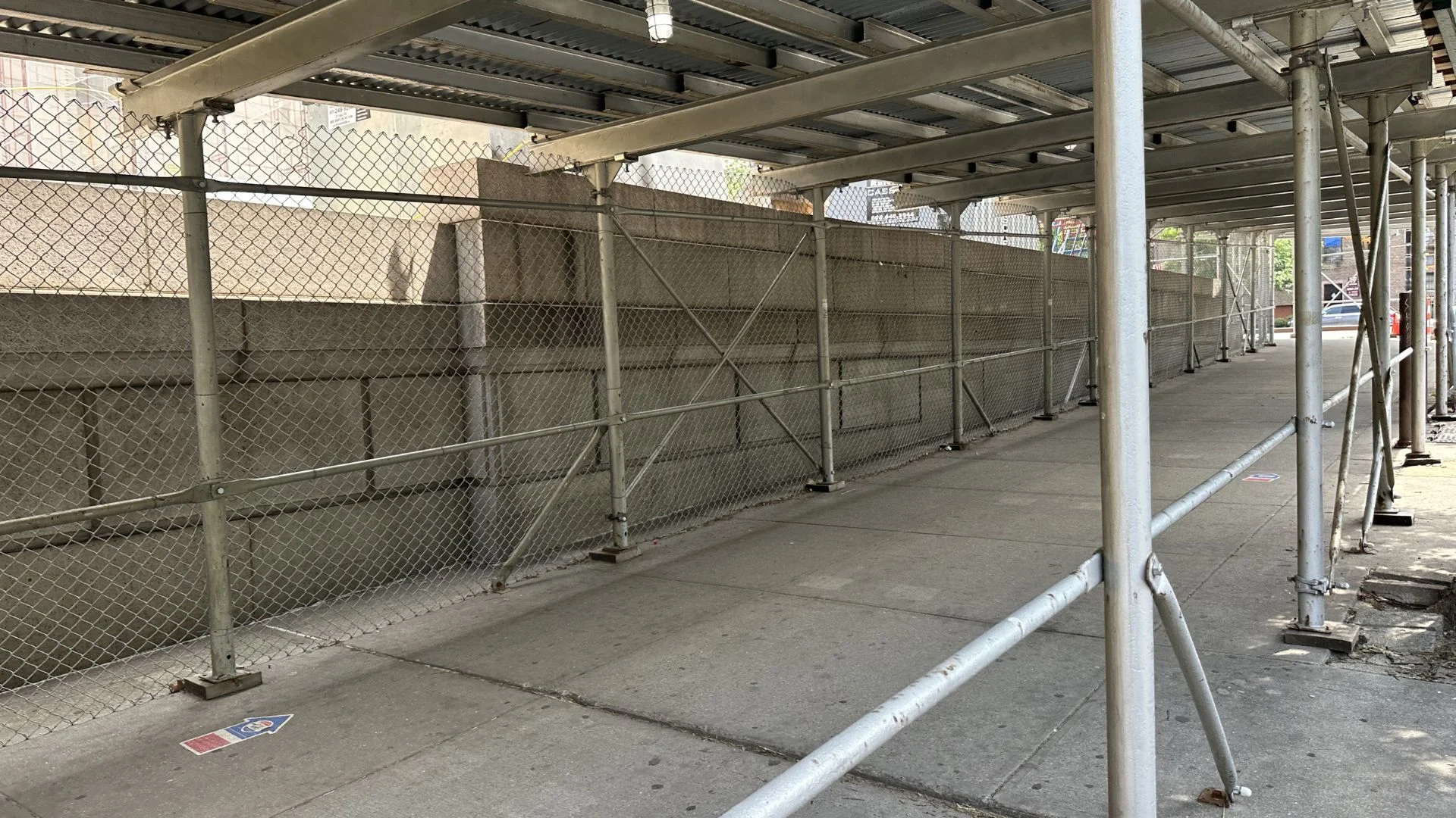 Sidewalk shed and scaffolding covering building entrance in NYC
